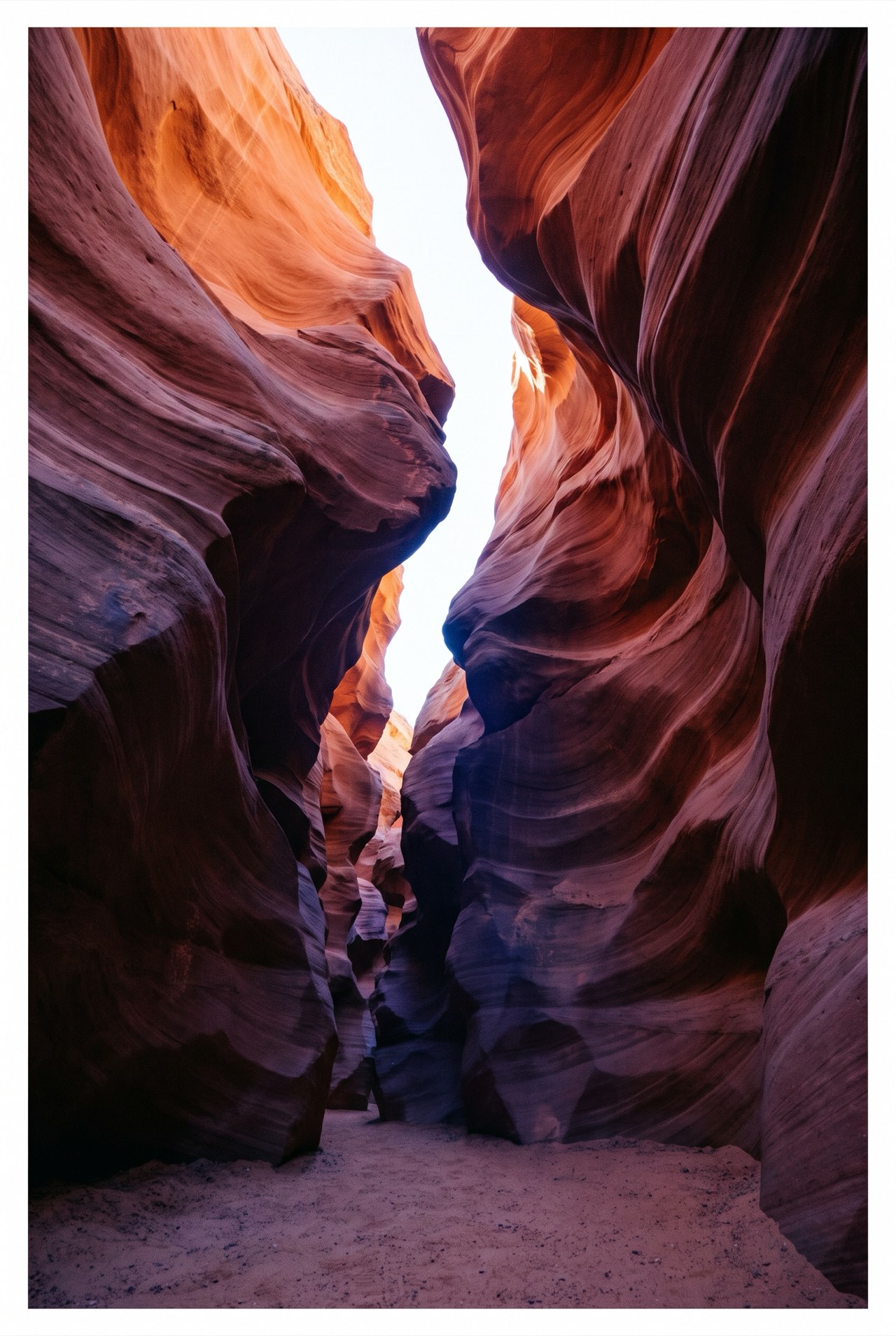 Looking up a narrow slot canyon where two sandstone walls almost meet around a thin seam of sky