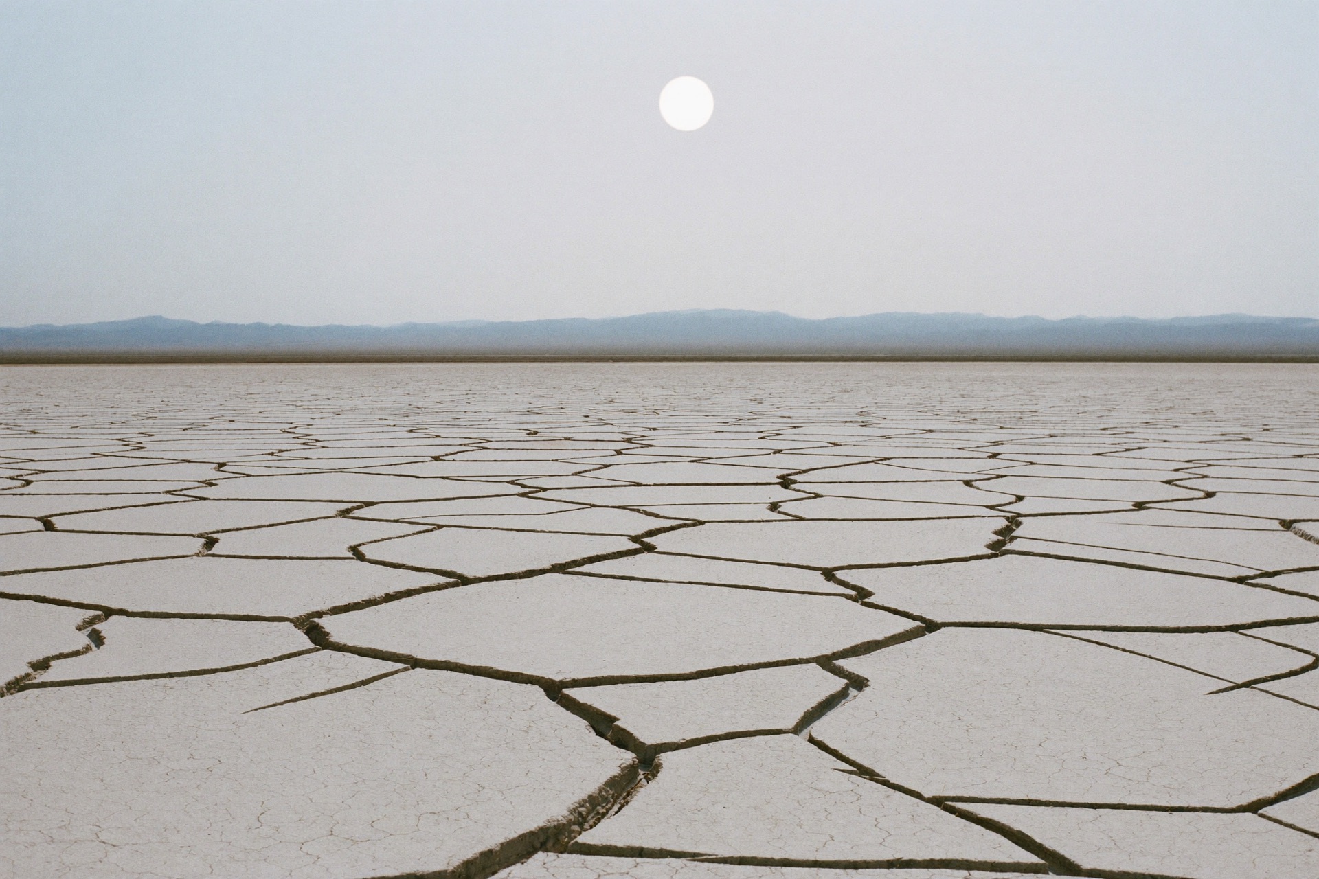 A vast cracked dry lakebed at midday stretching to a flat horizon